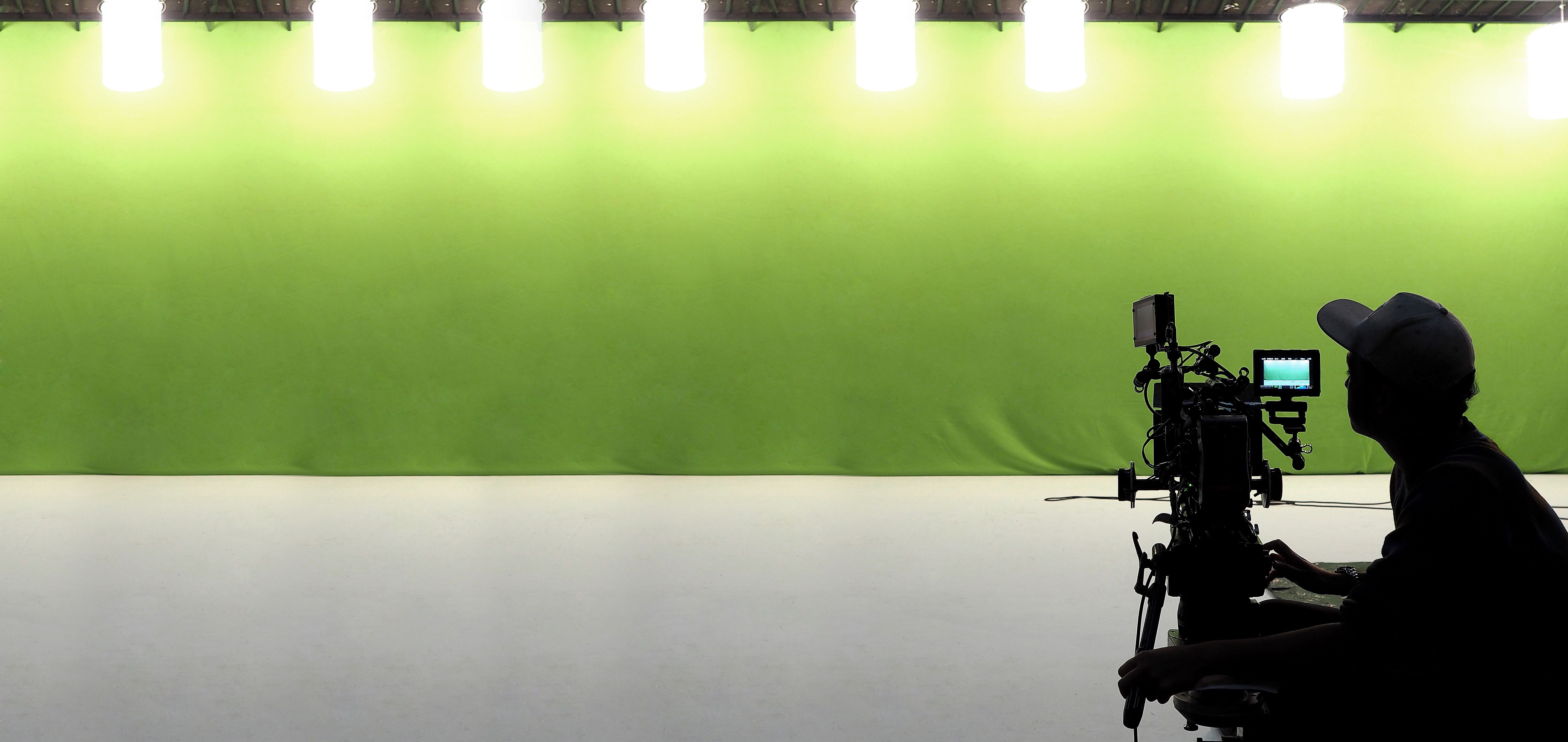 Camera man filming a video for a corporate client on a green screen